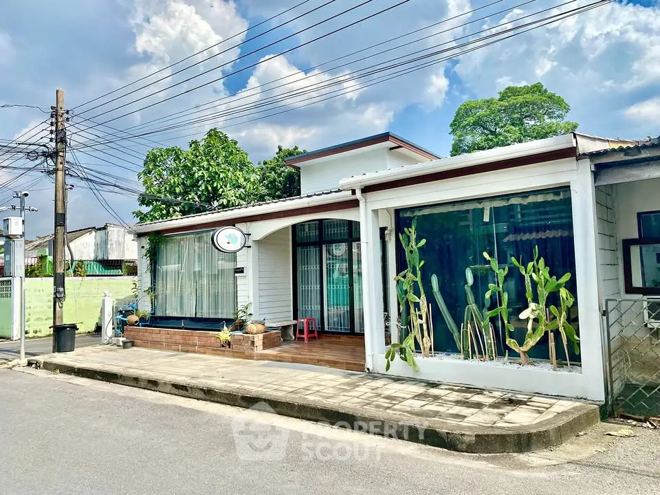 Charming single-story home with large windows and lush greenery on a quiet street.
