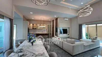 Luxurious open-plan living room with modern kitchen and elegant dining area, featuring stylish lighting and marble flooring.