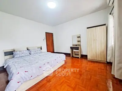 Spacious bedroom with wooden flooring and modern furniture in a cozy apartment.