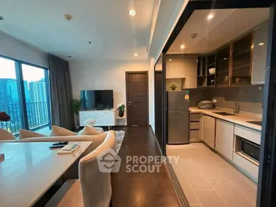 Modern open-plan living room and kitchen with city view, stylish furniture, and sleek appliances.
