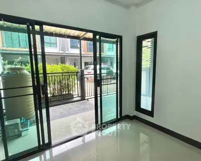 Spacious room with sliding glass doors leading to a private balcony, offering a view of the neighborhood.