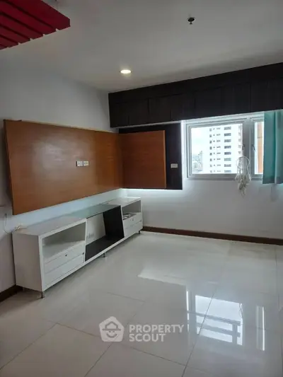 Spacious modern room with large window and built-in storage, ideal for versatile living.