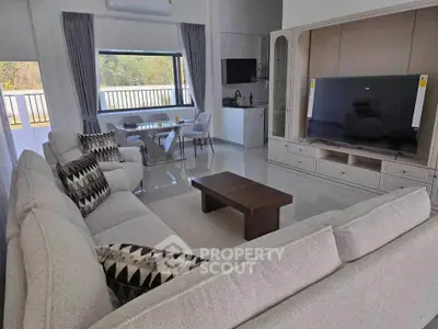 Spacious living room with modern decor and large TV, featuring a cozy sofa and dining area with scenic window view.