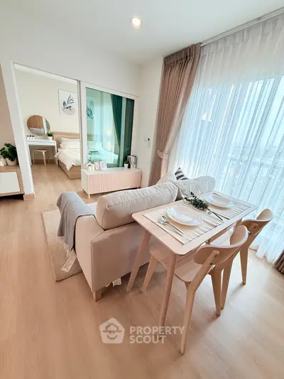 Modern open-plan living room with dining area and view into cozy bedroom