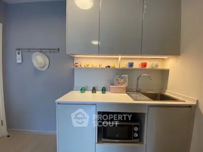 Modern compact kitchen with sleek cabinetry and built-in microwave, perfect for urban living.