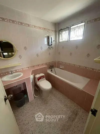 Charming vintage bathroom with pink tiles and bathtub, perfect for a cozy home.