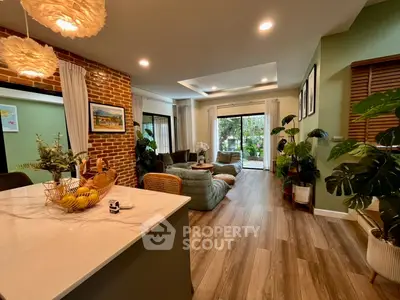 Stylish open-plan living room with modern decor and lush greenery view.