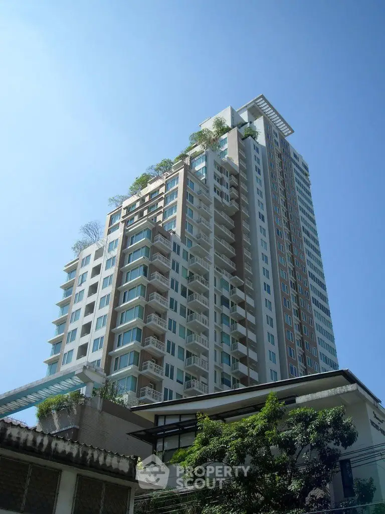 Stunning high-rise building with modern architecture and lush greenery on balconies.