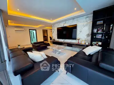Luxurious modern living room with marble accents and sleek black leather sofas.