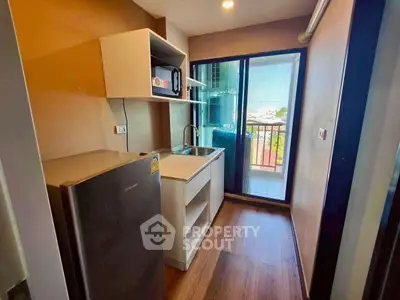 Compact kitchen with modern appliances and balcony view in urban apartment
