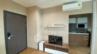 Modern apartment interior with compact kitchen and cozy living area featuring air conditioning.