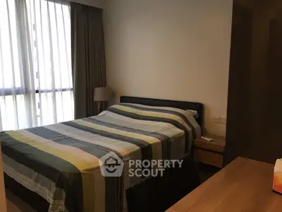 Cozy bedroom with modern decor and large window for natural light.