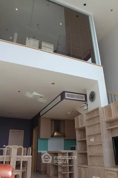 Spacious modern living room with high ceiling and open kitchen layout in luxury apartment.