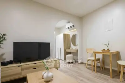 Modern living room with minimalist decor and wooden furniture, featuring a TV and a small dining area.