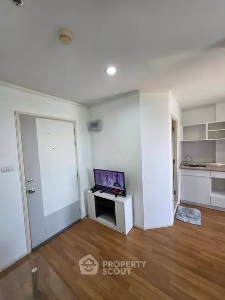 Modern apartment interior with wooden flooring, compact kitchen, and cozy living area.