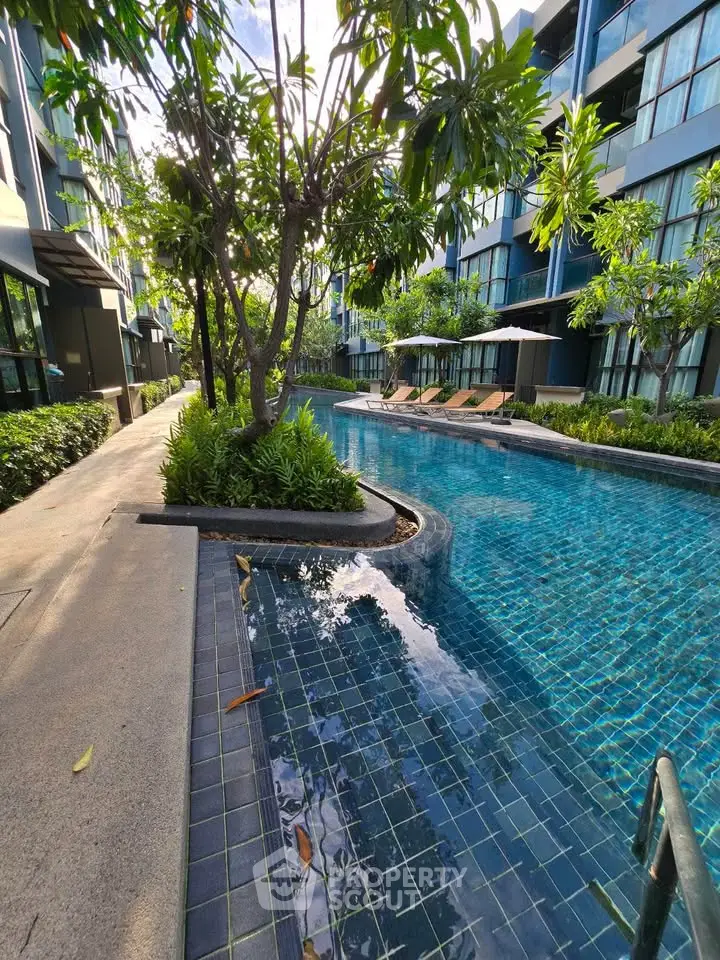 Luxurious condominium pool area with lush greenery and modern design, perfect for relaxation and leisure.