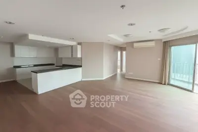 Spacious open-plan living area with modern kitchen and balcony access.