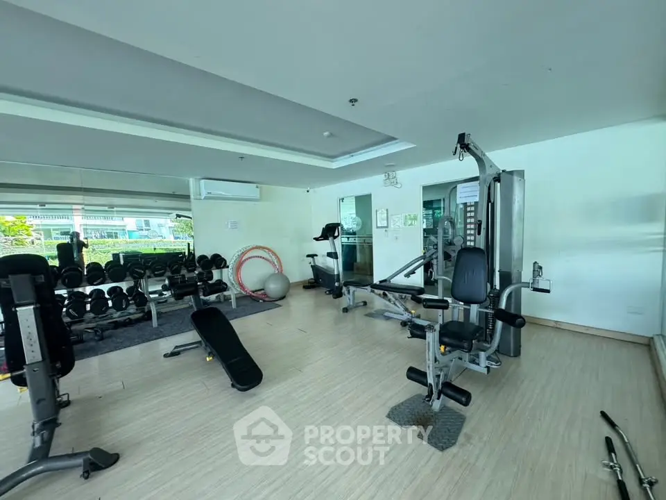 Spacious gym with modern equipment in a residential building, perfect for fitness enthusiasts.