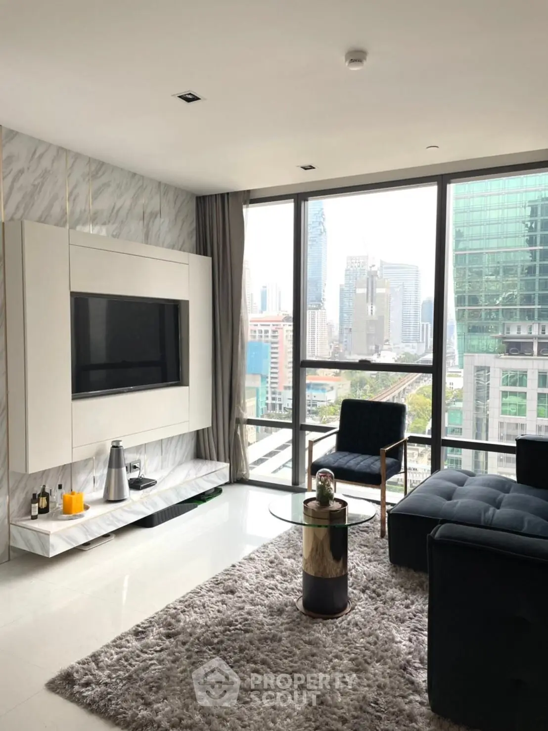 Luxurious modern living room with city view, featuring sleek furniture and large windows.