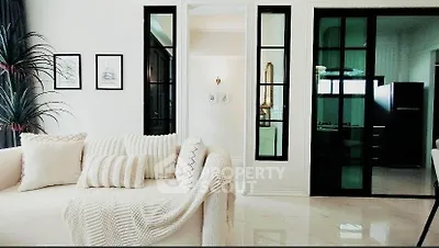 Elegant living room with modern decor and cozy sofa, featuring stylish black-framed glass doors.