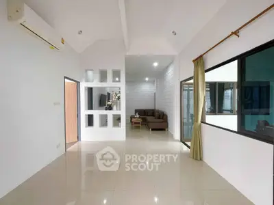 Spacious modern living area with sleek tile flooring and cozy seating, perfect for relaxation and entertainment.