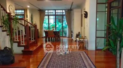 Spacious living room with wooden floors and large windows overlooking greenery