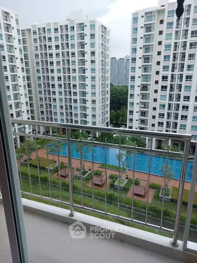 Modern apartment balcony with pool and garden view in high-rise complex.