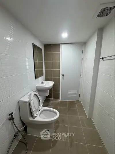 Modern bathroom with sleek fixtures and neutral tiles, featuring a toilet and sink.