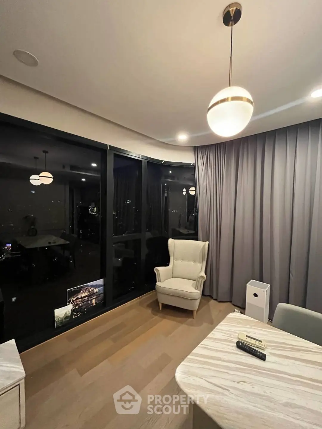 Elegant living room with modern lighting and large windows offering a stunning night view.