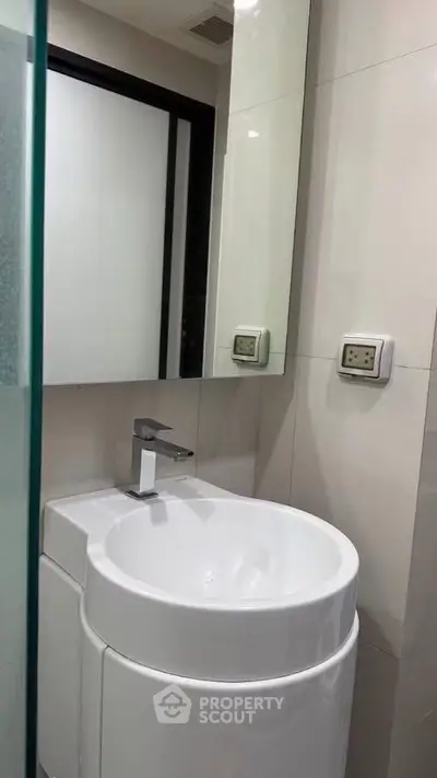 Modern compact bathroom with sleek sink and mirror in contemporary apartment.