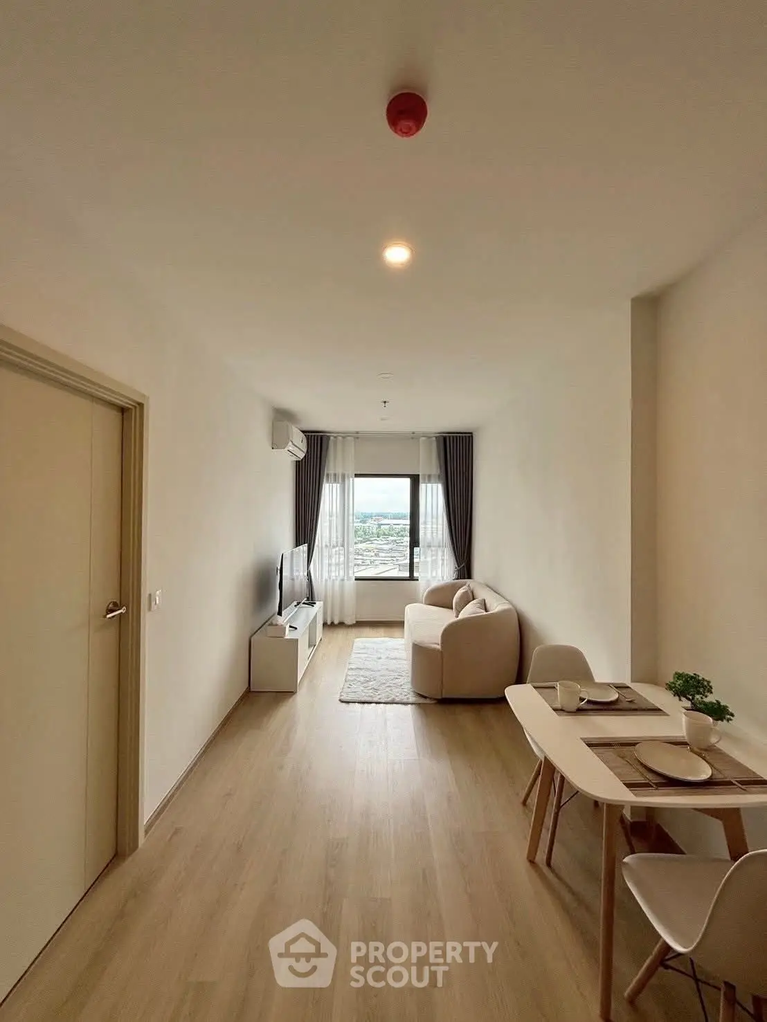 Modern living room with cozy seating and dining area, featuring a large window with a view.