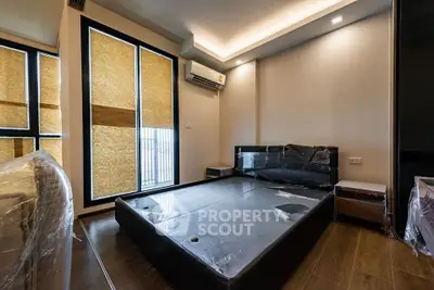 Modern bedroom with sleek design and large windows, featuring a stylish bed and air conditioning.