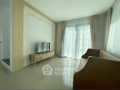 Modern living room with sleek TV stand and elegant curtains, featuring natural light and stylish armchairs.