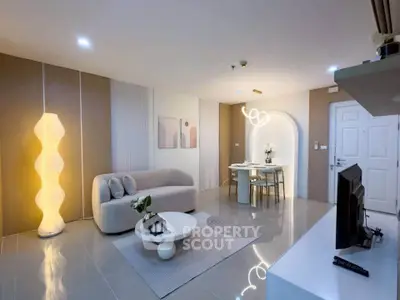 Modern living room with stylish decor and open dining area, featuring elegant lighting and contemporary furniture.