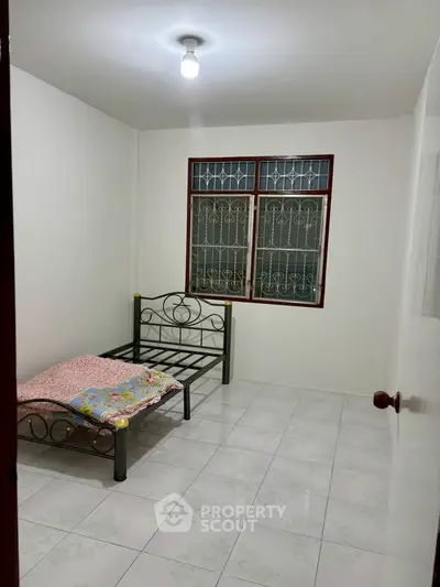 Cozy bedroom with metal bed frame and tiled floor, ideal for minimalist living.