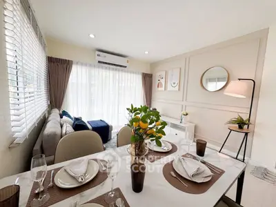 Elegant living room with dining area, featuring modern decor and abundant natural light.