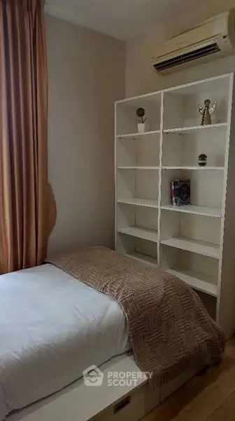 Cozy bedroom with built-in shelving and air conditioning, perfect for a comfortable living space.