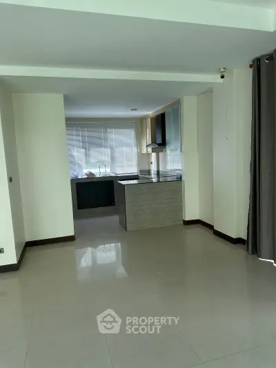 Spacious open-plan living area with modern kitchen and large windows for natural light.