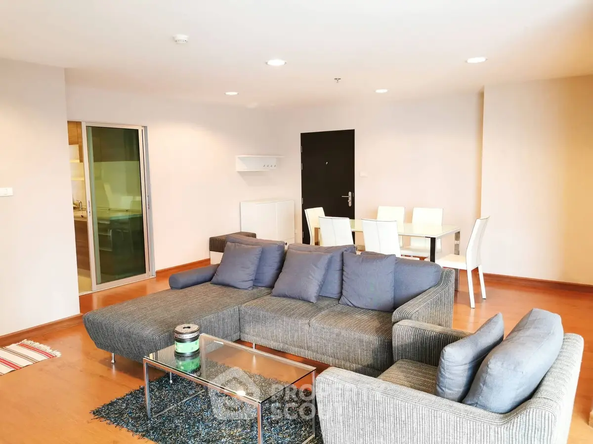 Spacious modern living room with stylish gray sofa and dining area, perfect for entertaining.