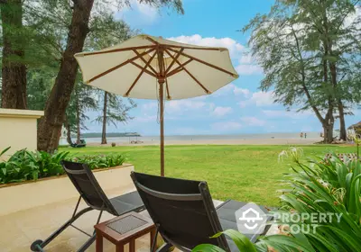 Beachfront patio with sun loungers and umbrella overlooking serene ocean view