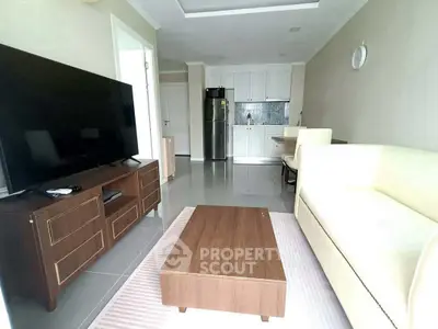 Modern living room with sleek furniture and open kitchen layout, featuring a large TV and stylish decor.