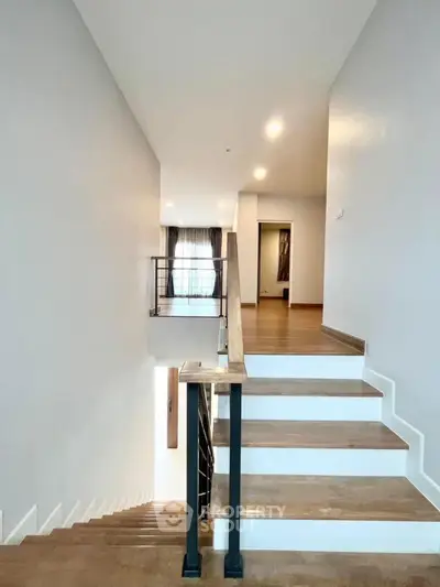 Spacious modern staircase with wooden steps and sleek railing in a contemporary home