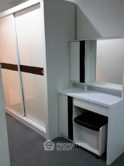 Modern bedroom with sleek wardrobe and stylish vanity in a compact space.