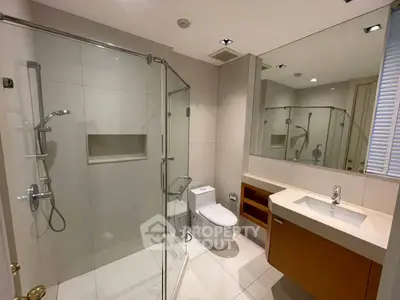Modern bathroom with glass shower, sleek vanity, and neutral tiles in a contemporary home.