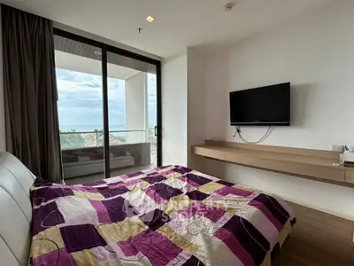 Cozy bedroom with modern decor and stunning balcony view of the ocean, perfect for relaxation.