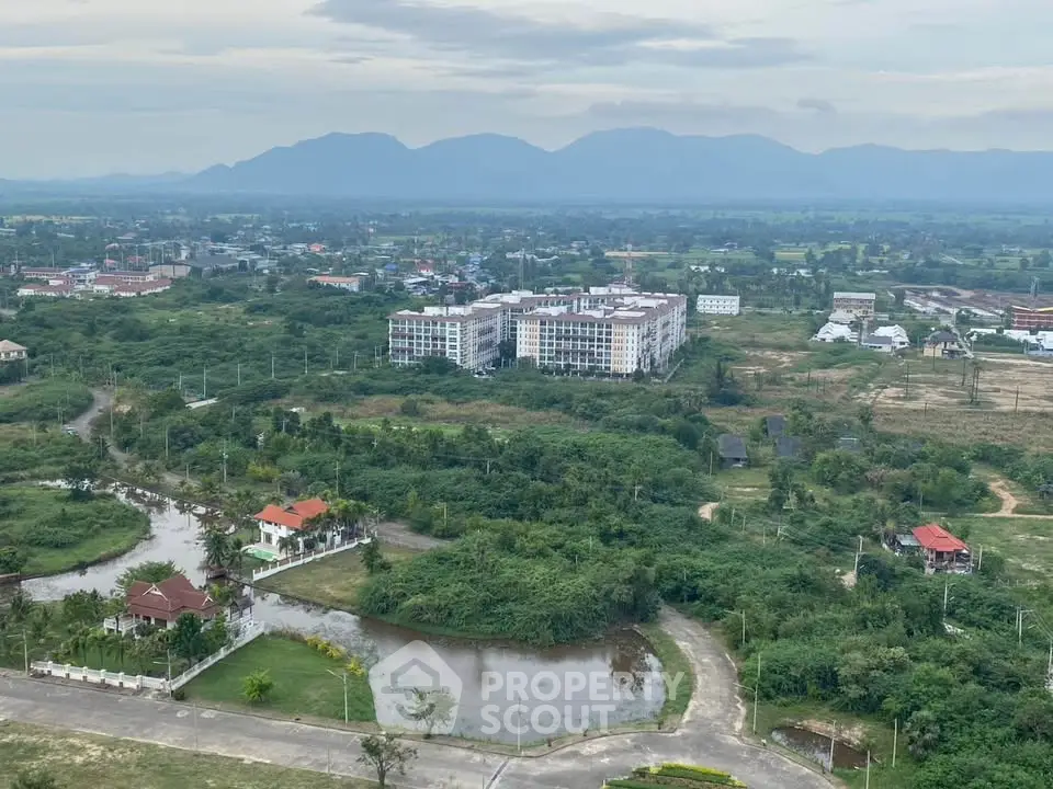 Scenic aerial view of residential area with lush greenery and distant mountains.