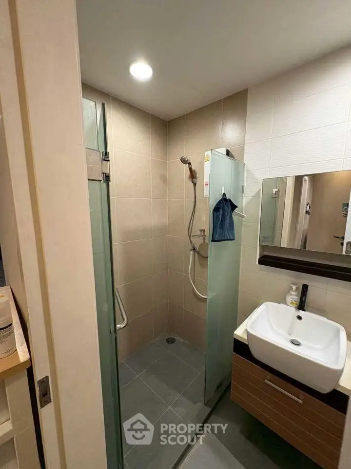 Modern bathroom with glass shower enclosure and sleek vanity in contemporary apartment.