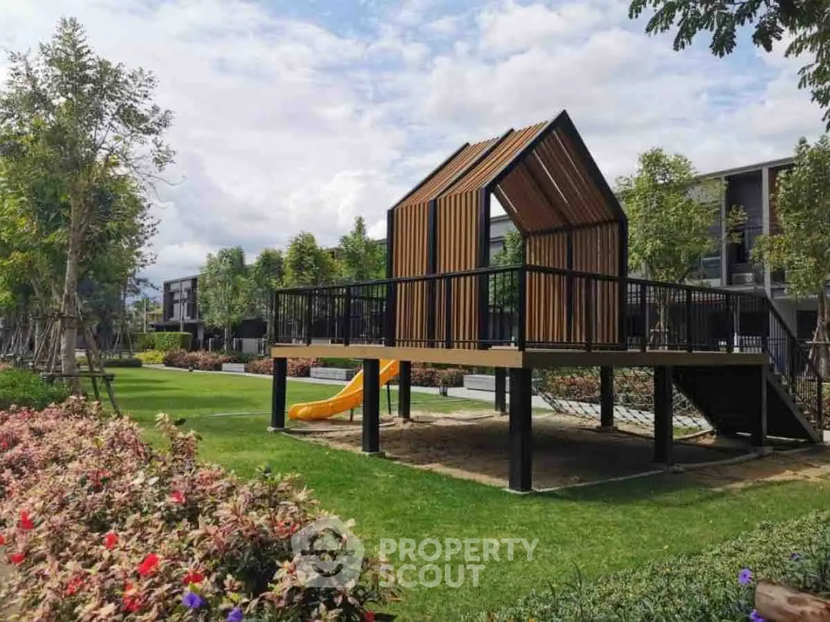 Modern playground structure in lush garden setting with vibrant greenery.