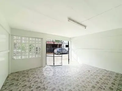 Spacious garage with tiled flooring and gated entrance, perfect for secure parking.