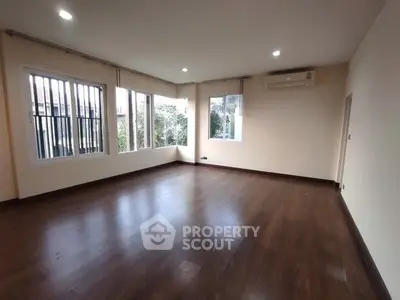 Spacious empty living room with hardwood floors and large windows.